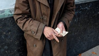 Пожилой человек считает деньги в центре Киева