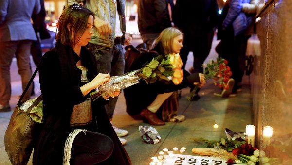 Люди возлагают цветы на импровизированный мемориал в честь жертв терактов в Париже