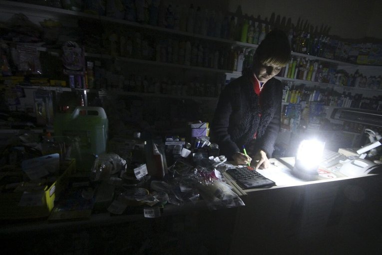Продавец работает в хозяйственном магазине при свечах из-за отключения электричества в Симферополе