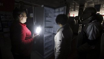 Сотрудник общается с покупателями в магазине электроники при свечах в Симферополе