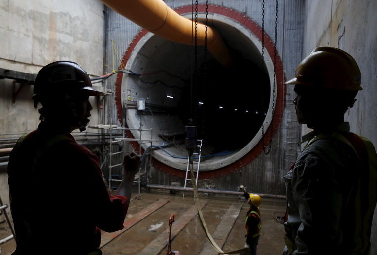 Рабочие стоят рядом со строящимся тоннелем системы скоростного транспорта в Джакарте