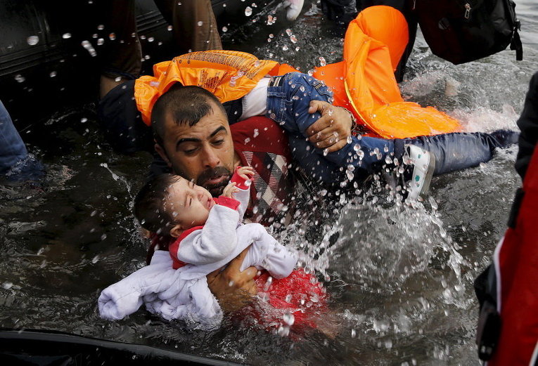 Сирийский беженец и его дети по прибытии на греческий остров Лесбос после пересечения части Эгейского моря из Турции