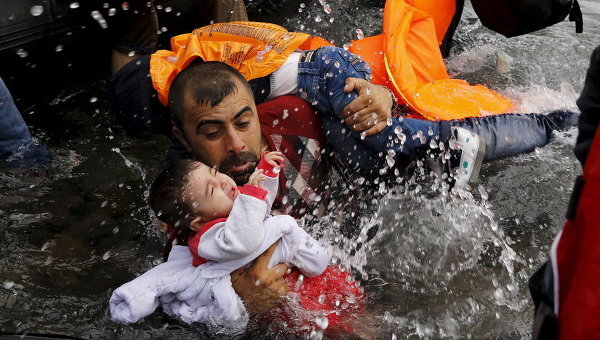 Сирийский беженец и его дети по прибытии на греческий остров Лесбос после пересечения части Эгейского моря из Турции