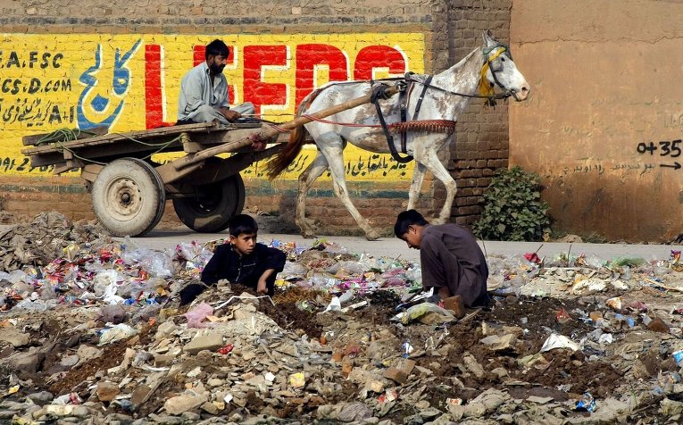 Пакистанские подростки роются в куче мусора в Пешаваре