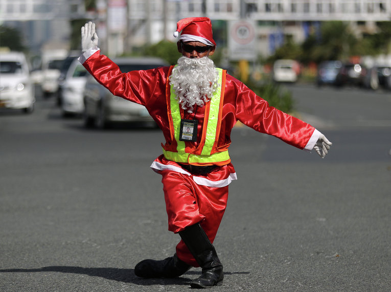 Регулировщик дорожного движения в столице Филиппин, Маниле, переоделся в костюм Санта-Клауса