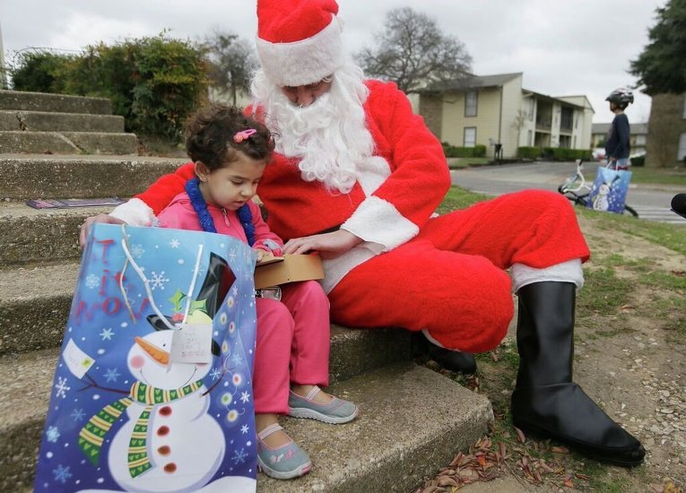 Санта-Клаус вручает подарок ребенку-беженцу в Далласе
