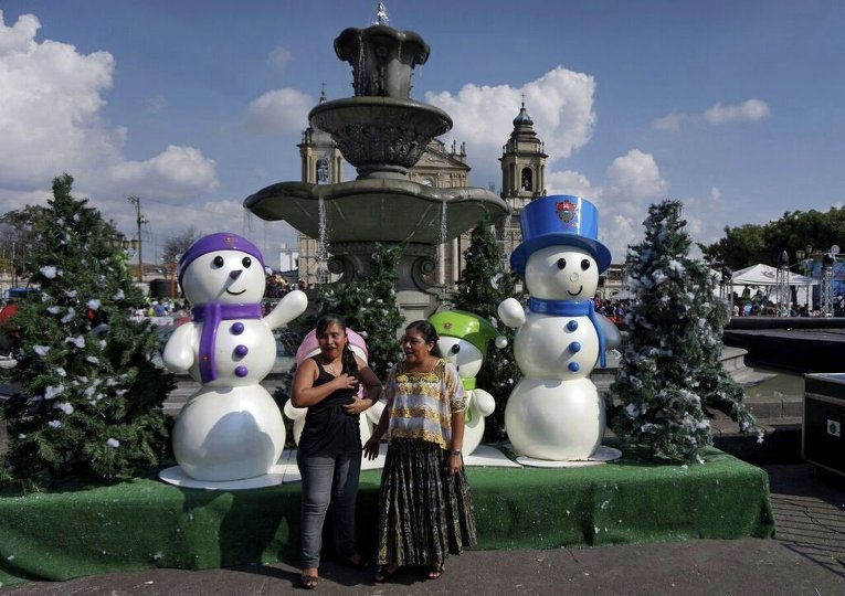 Две женщины фотографируются возле снеговиков в Гватемале