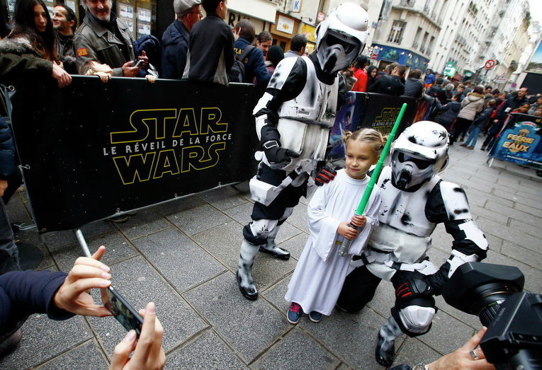 Девочка позирует рядом с одетым в героя фильма мужчиной после утреннего показа Star Wars: The Force Awakens в кинотеатре Grand Rex в Париже