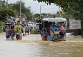 Жители пробираться через затопленную улицу после проливного дождя в городе Кандаба, к северу от Манилы