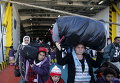 Беженцы и переселенцы прибывают на пароме с острова Лесбос в порту Пирей, вблизи Афин, Греция