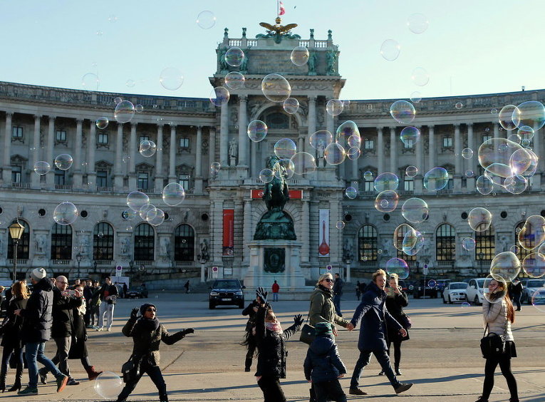 Дети пытаются поймать мыльные пузыри перед дворцом Хофбург в Вене