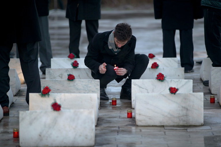 Человек зажигает свечу у мемориала в память о 37 жандармах, убитых армейскими войсками во время антикоммунистического восстания в 1989 году в Отопень, Румыния