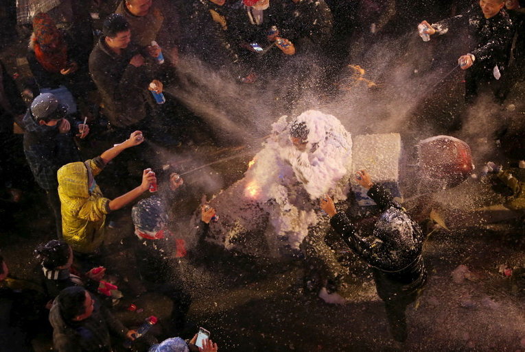 Люди брызгают из баллончиков с искусственным снегом во время празднования Рождества в Китае