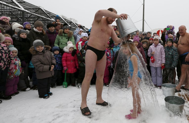 Житель российского Красноярска Григорий Броверман, член группы зимних пловцов клуба Cryophile, выливает ведро ледяной воды на свою 6-летнюю дочь Лизу при температуре воздуха минус 5.
