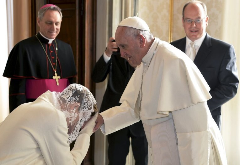 Принцесса Монако Шарлин целует руку Папе Римскому Франциску во время частной аудиенции в Ватикане.