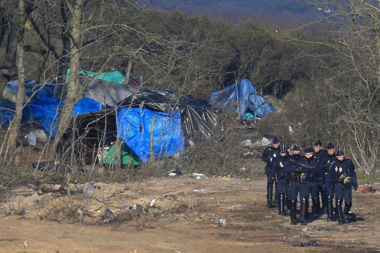 Французские полицейские рядом с лагерем беженцев в Кале