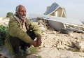 Палестинец сидит на развалинах своего дома.