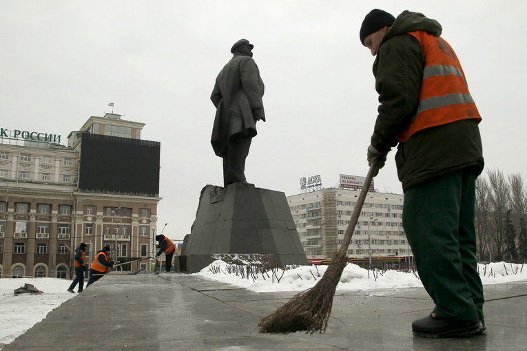 Работники подметают улицу рядом с памятником Ленину, который был частично поврежден при взрыве в центре Донецка