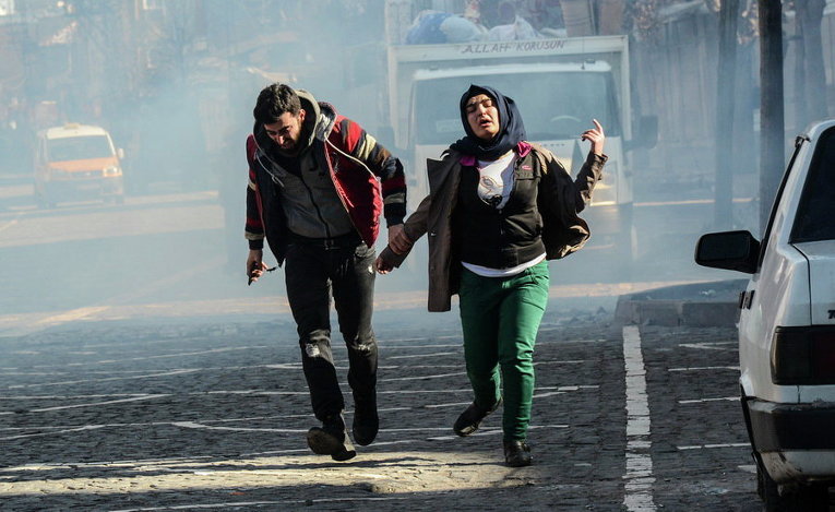 Жители бегут в укрытие от слезоточивого газа, выпущенного силами безопасности после введения комендантского часа в Сурат, Турция