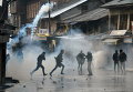 Индийские протестующие Кашмира бегут от слезоточивого газа во время столкновений в центре Шринагар