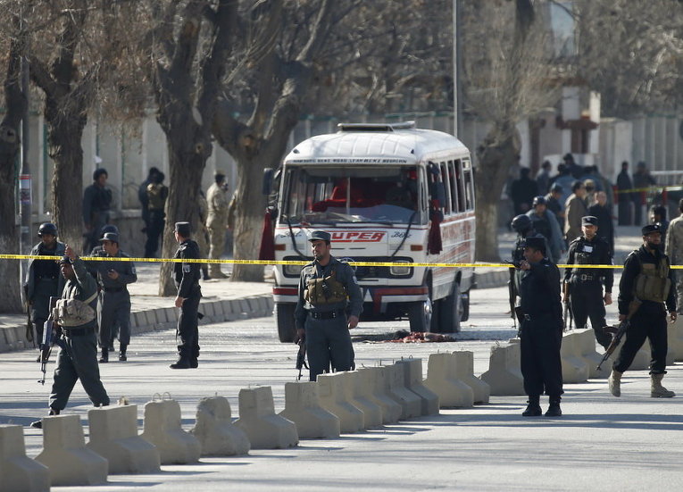 Афганские полицейские стоят на страже вокруг поврежденного мини-автобуса на месте теракта в Кабуле, Афганистан