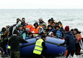Волонтеры тянуть лодку с беженцами и мигрантами на пляже на греческом острове Лесбос