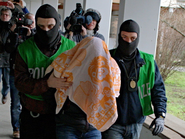 Члены немецкой полиции с подозреваемым, задержанным в ходе рейда в Берлине, Германия