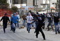 Палестинцы бросают камни в израильских военных в ходе столкновений в лагере беженцев к северу от города Хеврон