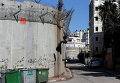 Палестинец поднимается с помощью веревки на разделительный барьер, отделяющий Западный берег от Иерусалима