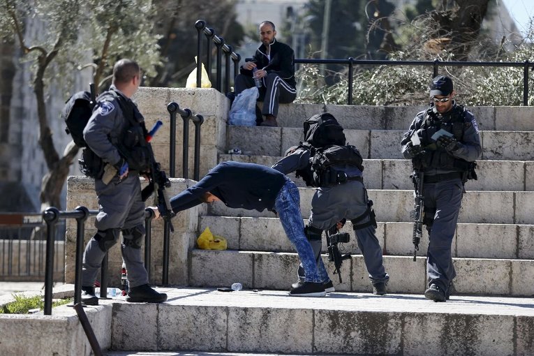 Израильская полиция проводит досмотр личных вещей палестинца, задержанного в Старом городе Иерусалима.