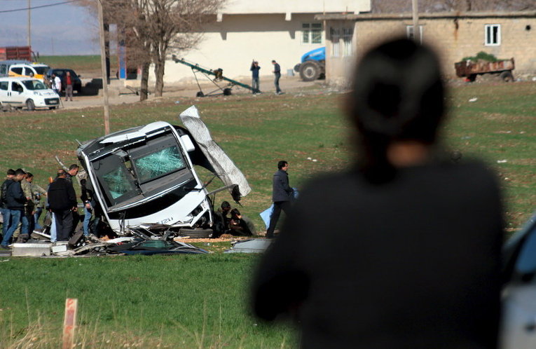 Солдаты и офицеры безопасности стоят рядом с поврежденным взрывом военным автомобилем возле Диярбакыр, Турция