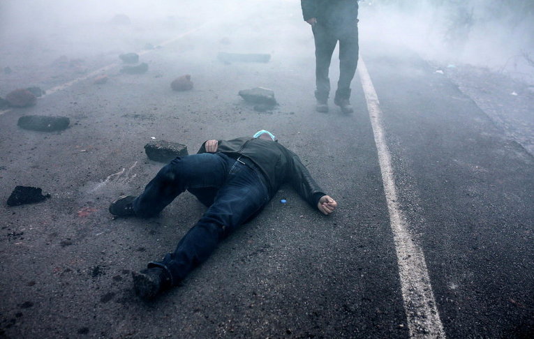 Протестующий в маске лежит на земле после того, как полиция применила слезоточивый газ во время демонстрации против строительства шахты в Артвин, Турция