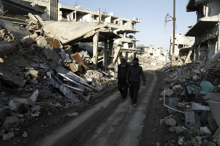 Сирийские мужчины идут по восточной окраине Дамаска