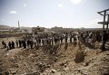 Люди собрались возле воронки, образовавшейся в результате авиаудара Саудовской Аравии по столице Йемена.