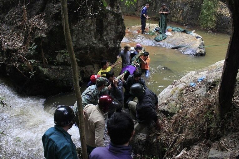 Спасатели несут одно из тел британских туристов, найденных мертвыми возле водопада на окраине высокогорного города Далат во Вьетнаме