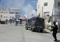 Палестинские протестующие перед израильскими пограничниками во время демонстрации против закрытия улицы Шухада для палестинцев