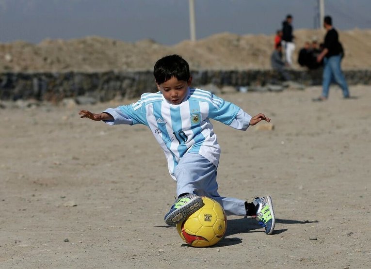 Пятилетний Муртаза Ахмади, поклонник Лионеля Месси, играет на открытой площадке в Кабуле в рубашке, подписанной знаменитым футболистом