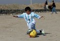 Пятилетний Муртаза Ахмади, поклонник Лионеля Месси, играет на открытой площадке в Кабуле в рубашке, подписанной знаменитым футболистом