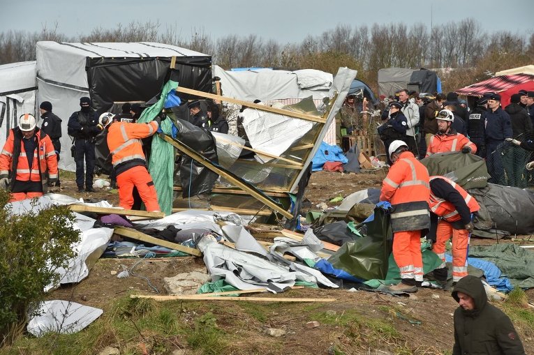 Демонтаж жилищ мигрантов в лагере для беженцев во французском Кале.