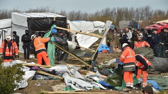 Демонтаж жилищ мигрантов в лагере для беженцев во французском Кале.