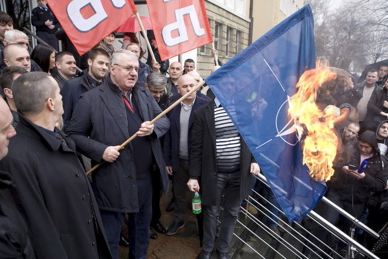 Сербский лидер ультра-националистов Воислав Шешель в окружении своих сторонников сжигает флаг НАТО во время акции протеста перед зданием Специального суда в Белграде