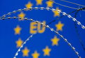 Колючая проволока на фоне символа Евросоюза