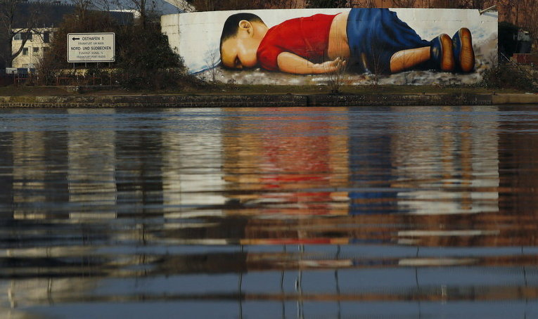 Огромное граффити, посвященное погибшему ребенку мигрантов, на стене на берегу реки Майн, недалеко от штаб-квартиры Европейского центрального банка во Франкфурте