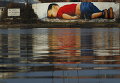 Огромное граффити, посвященное погибшему ребенку мигрантов, на стене на берегу реки Майн, недалеко от штаб-квартиры Европейского центрального банка во Франкфурте