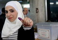 Сирийка показывает окрашенный чернилами большой палец после голосования на избирательном участке во время парламентских выборов в Дамаске