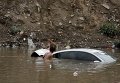 Люди пытаются вытащить автомобиль после паводков в столице Йемена Сане