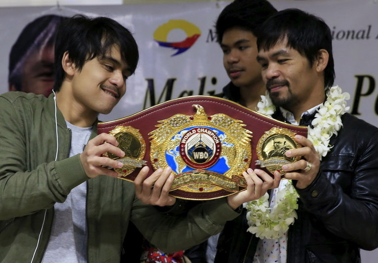 Филиппинский чемпион по боксу Пакьяо и его старший сын Джимвел показывают чемпионский пояс по прибытии в международный аэропорт имени Бениньо Акино в Маниле