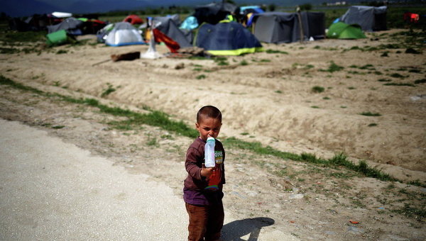 Мальчик пьет молоко в импровизированном лагере для мигрантов и беженцев на греко-македонской границы близ села Идомени, Греция