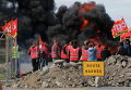 Сотрудники профсоюза нефтяного гиганта Total стоят возле горящих баррикад, чтобы заблокировать вход в депо компании вблизи нефтеперерабатывающего завода Donges, Франция
