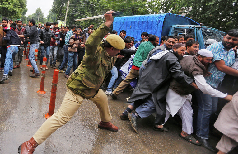 Индийский полицейский использует дубинки для разгона демонстрантов во время акции протеста государственных служащих, требующих изменений трудового законодательства.
